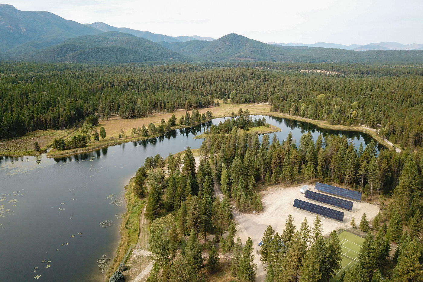 aerial view of lake and three large solar arrays