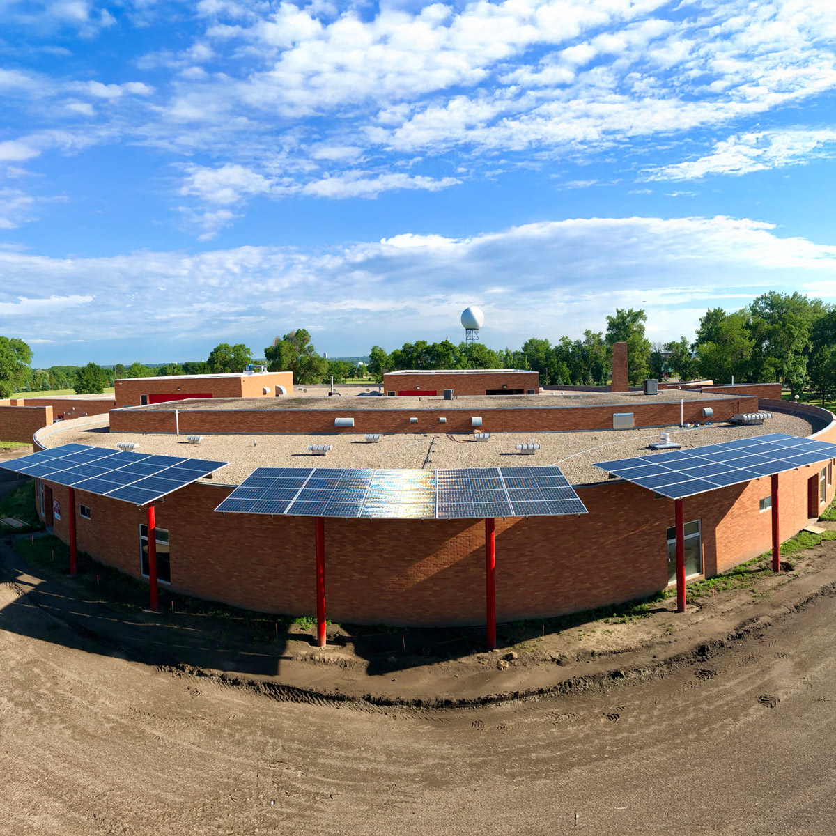 solar arrays on poles in front of a round school building