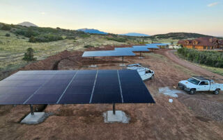 six solar arrays at a ranch with work trucks