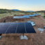 six solar arrays at a ranch with work trucks